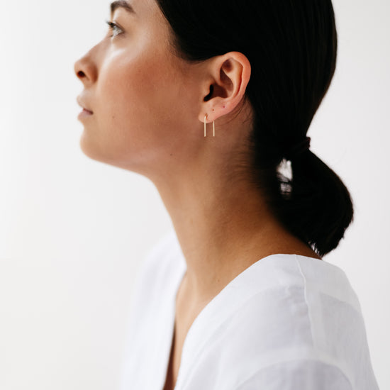 A pair of arch-shaped earrings made from Sterling silver and 9ct Gold on a model