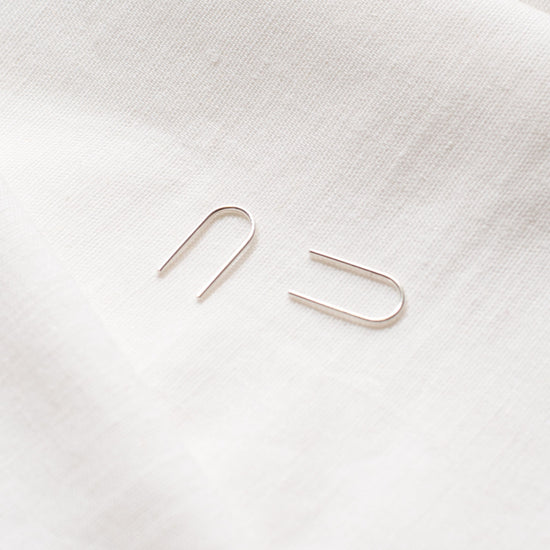 A pair of arch-shaped earrings made from Sterling silver and 9ct Gold, displayed against a light background.