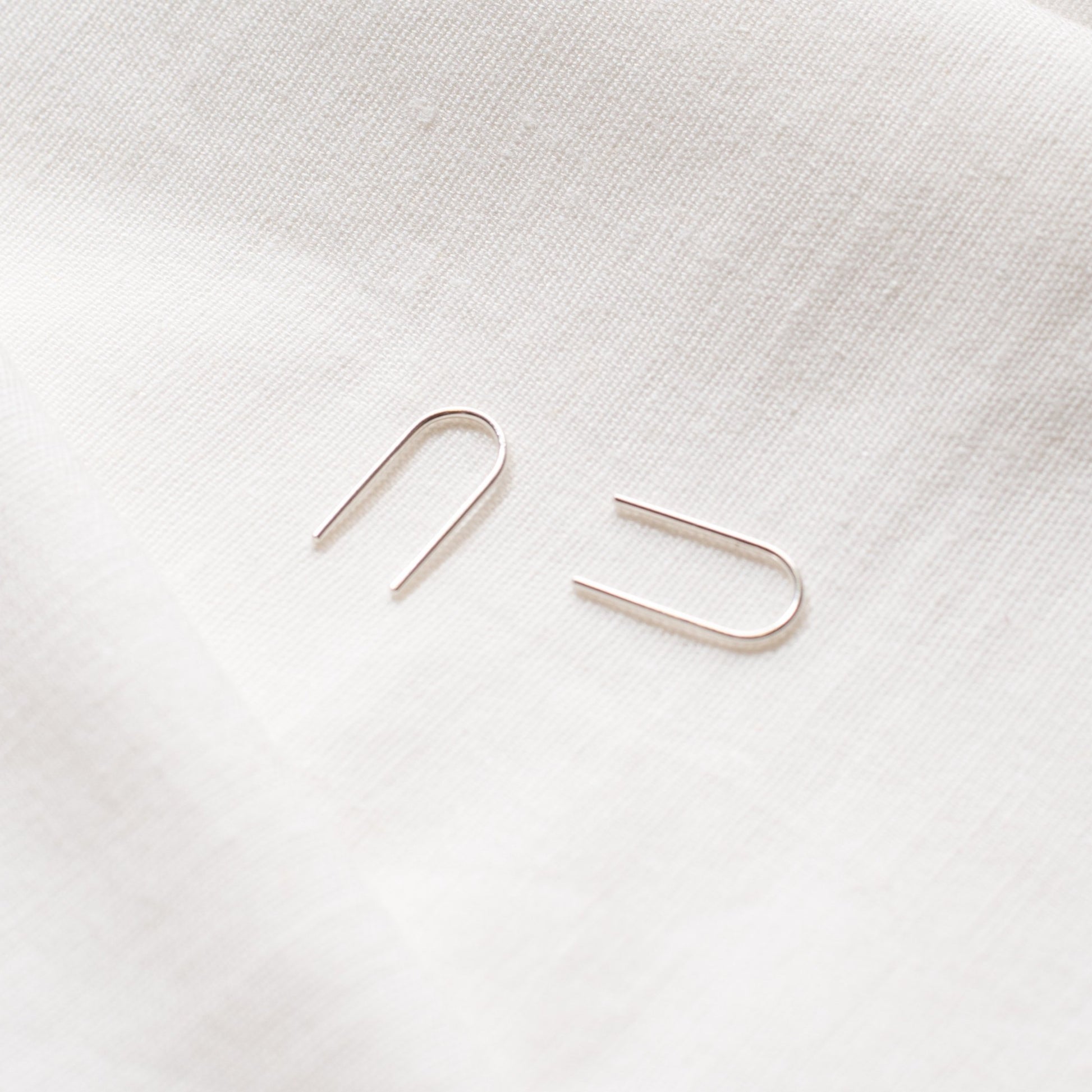 A pair of arch-shaped earrings made from Sterling silver and 9ct Gold, displayed against a light background.