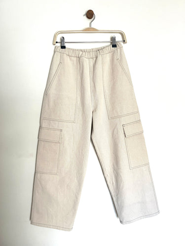 Ecru denim cargo trousers with two utility front pockets and two side patch packets with an elasticated waist band on a grey to white background