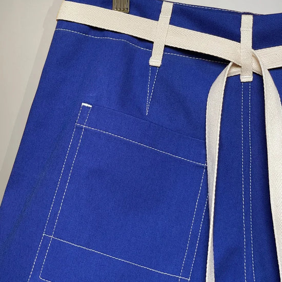 Blue trousers with a white belt hanging on a hook