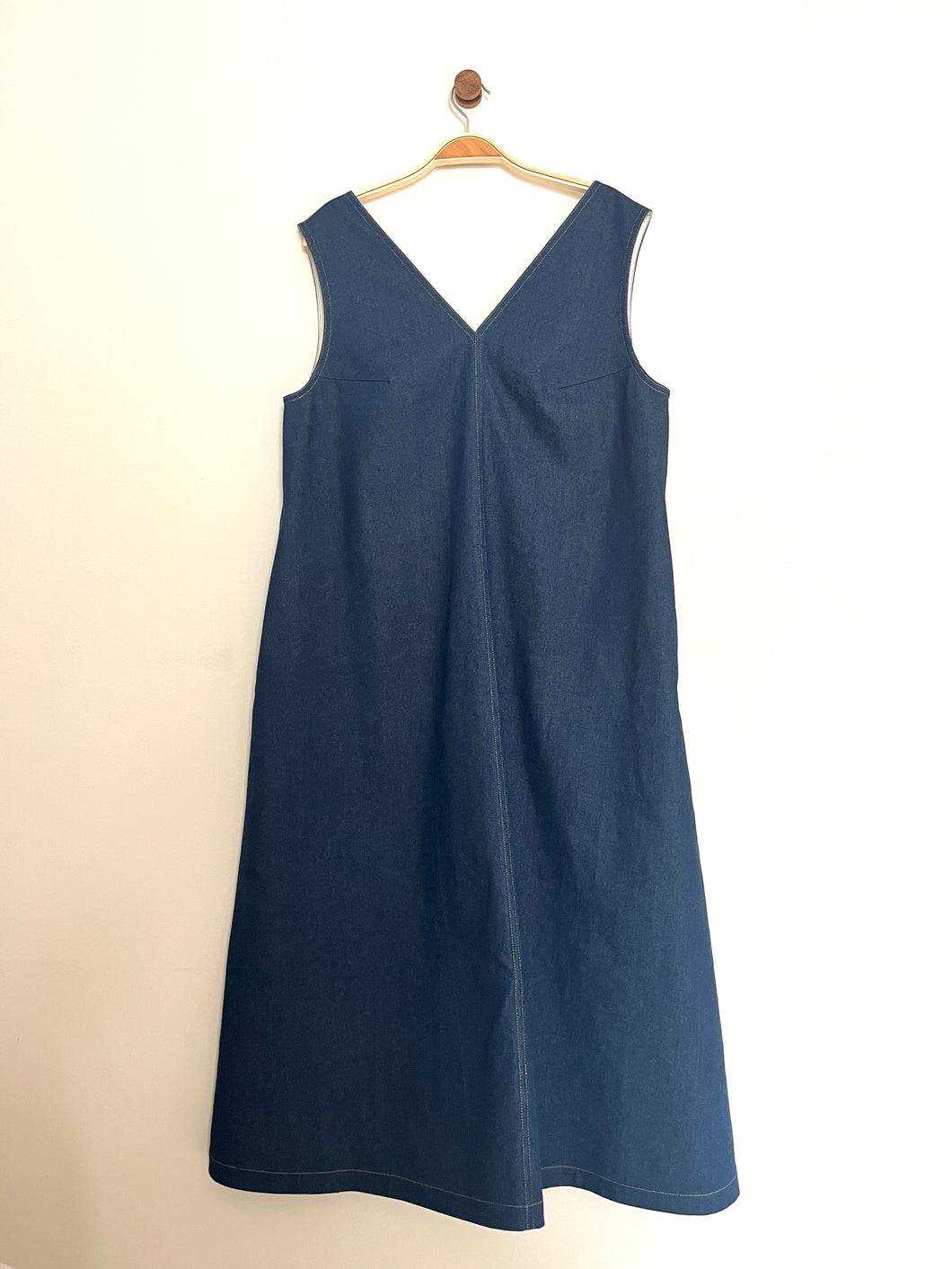 Indigo denim aline sleeveless long dress with a v-neck and centre seam on a cream background