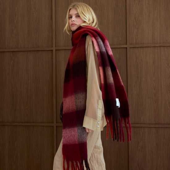 A woman wearing a brown and burgandy scarf on a brown background