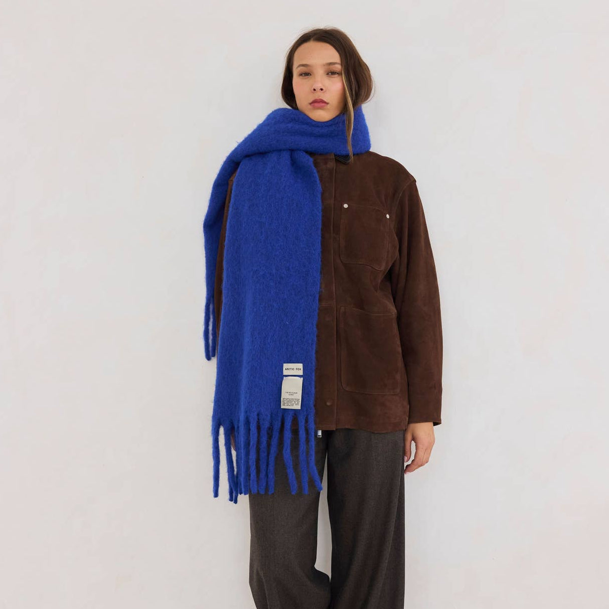 A woman wearing a brown outfit on a white background with a blue scarf