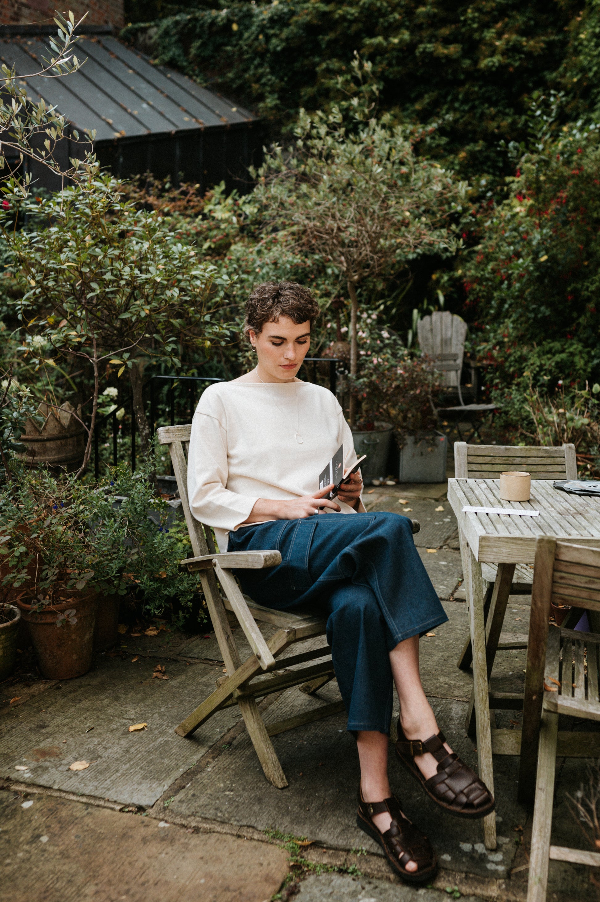 Woman sitting outdoors in a garden, using a tablet.