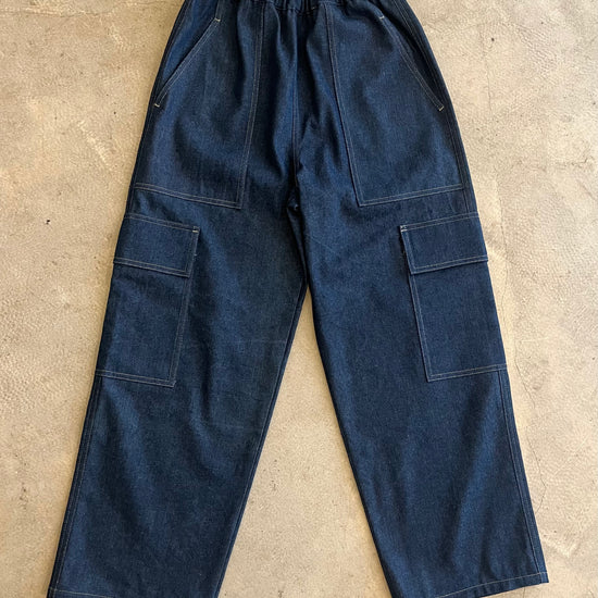 Blue denim work pants on a beige concrete floor