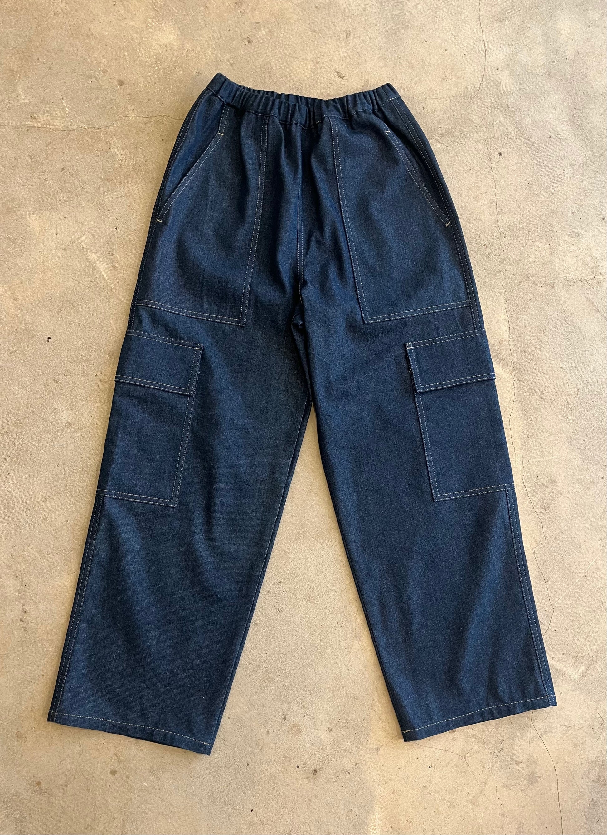 Blue denim work pants on a beige concrete floor