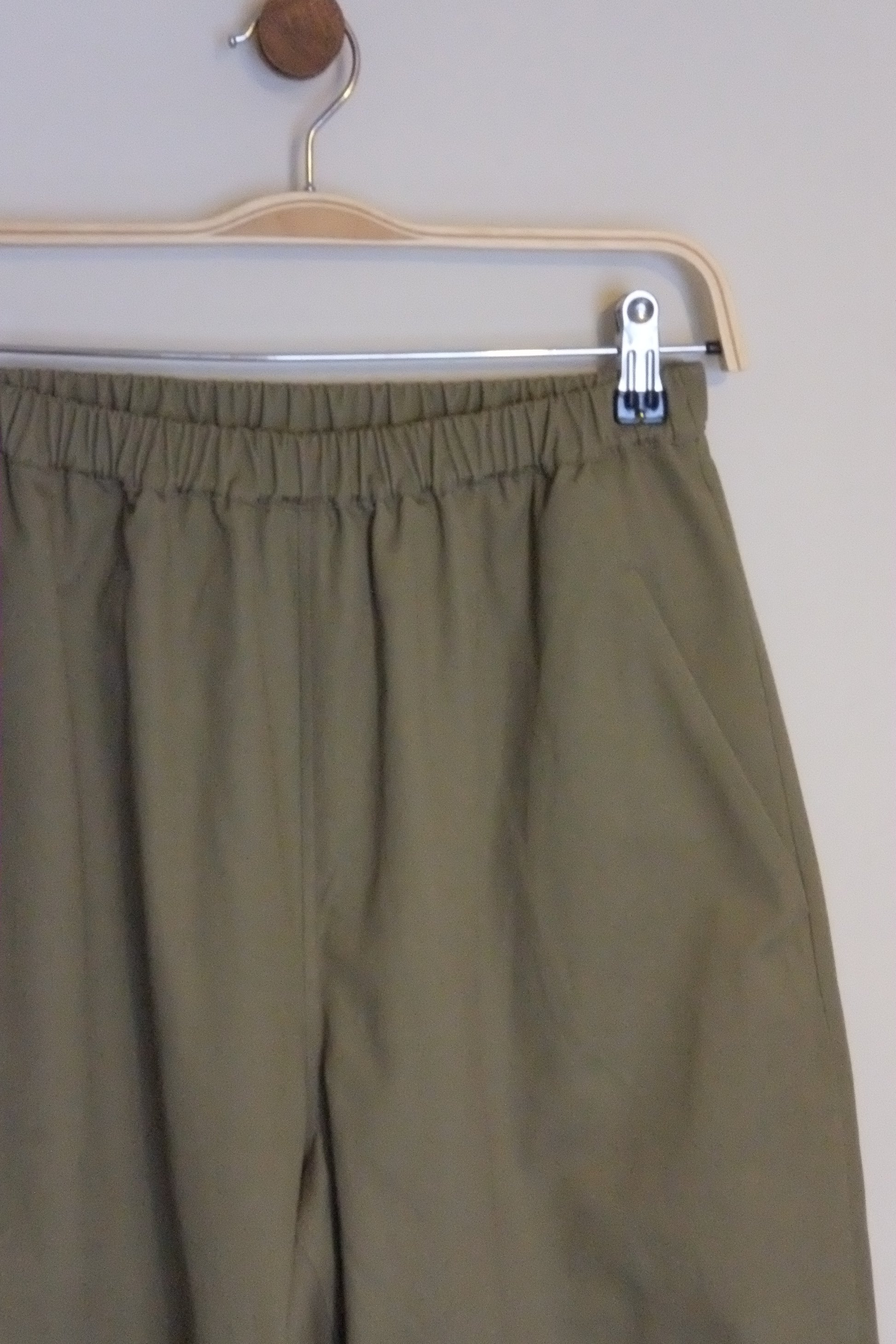 Green pants on a hanger against a neutral background