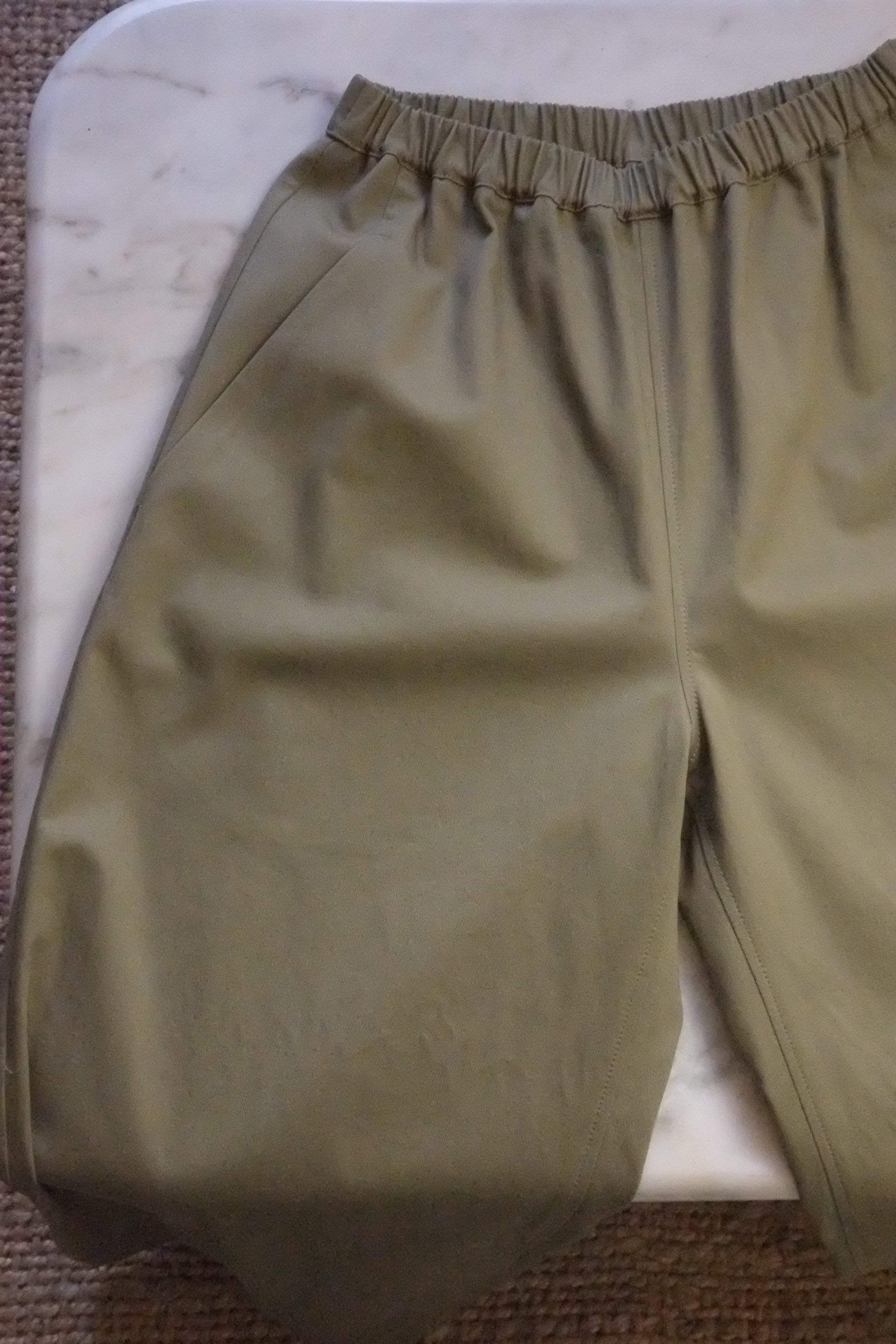 Green pants on a white surface with a brown textured background