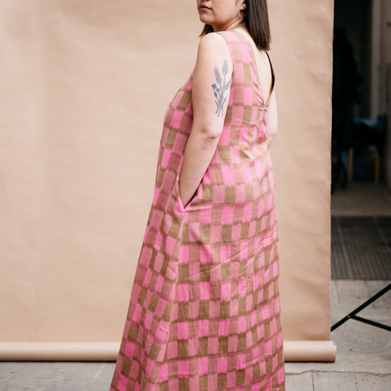 Person wearing a pink and brown checkered dress against a plain background