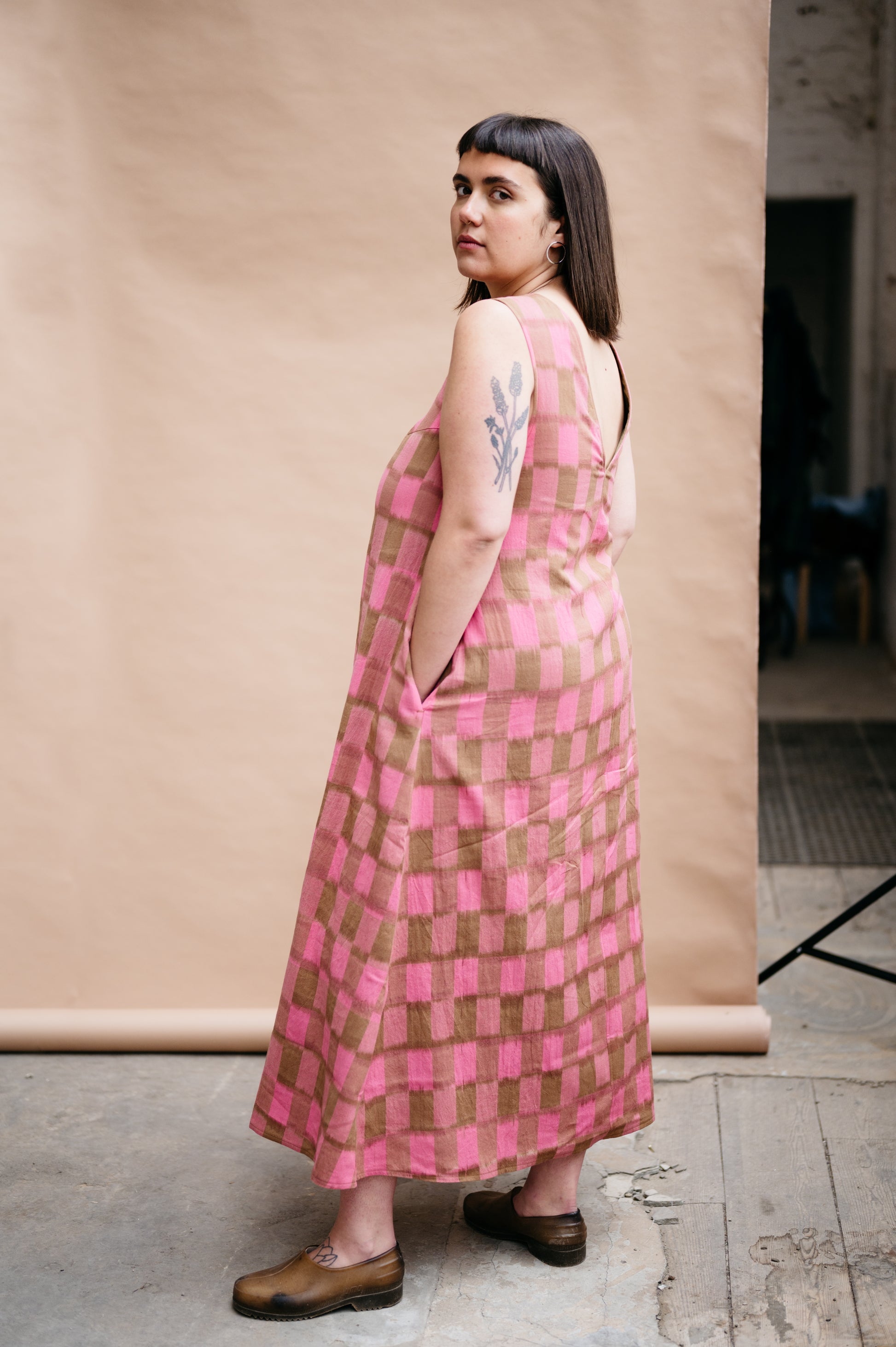 Person wearing a pink and brown checkered dress against a plain background