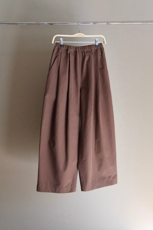 Brown pants hanging on a white hanger against a plain background