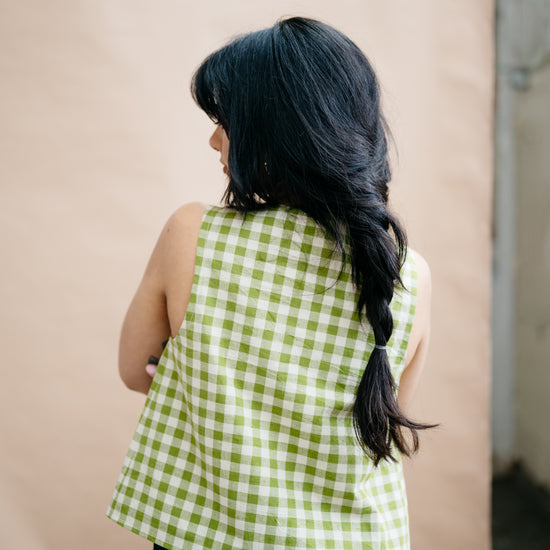 Person wearing a green checkered top against a plain background