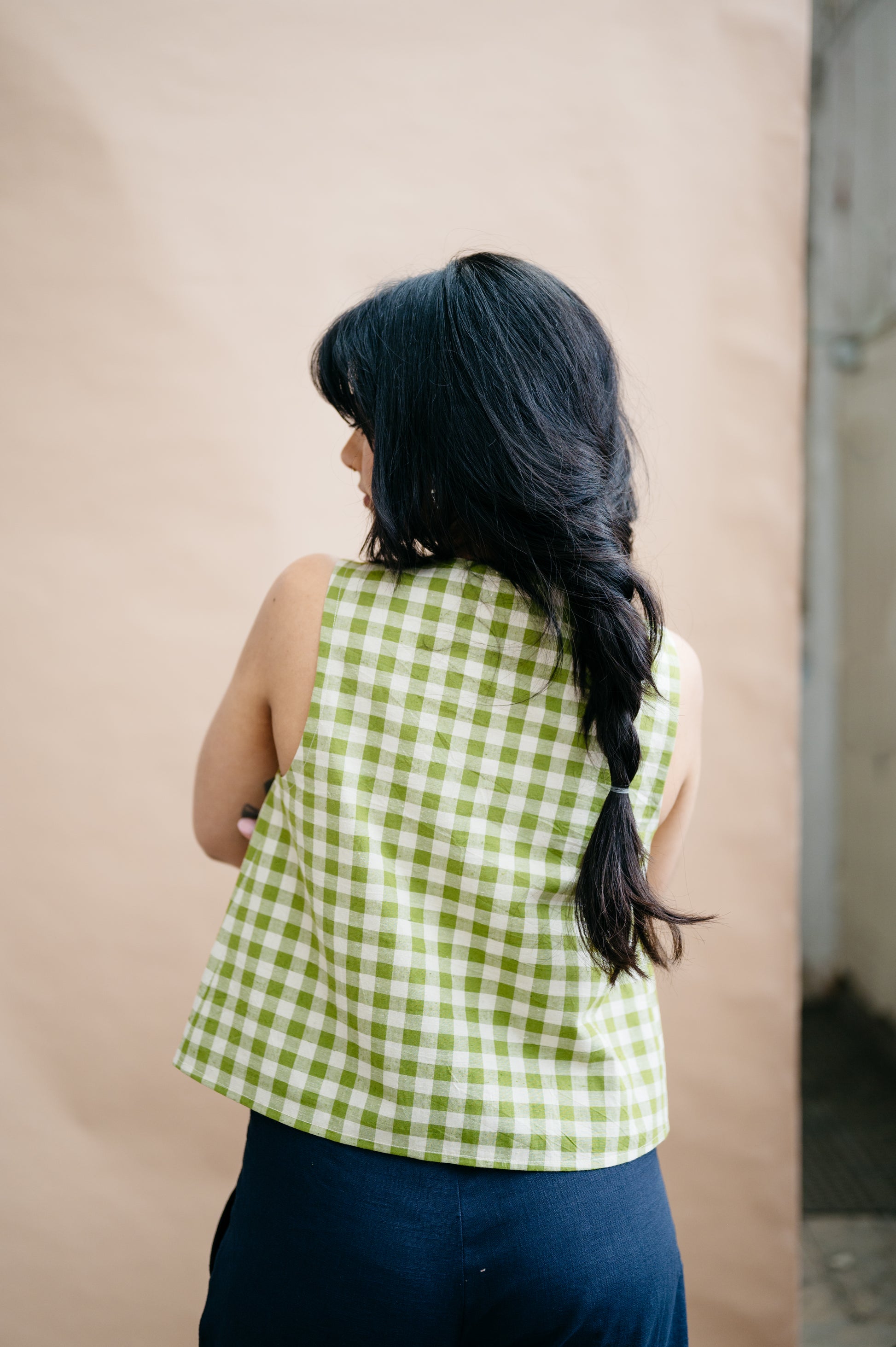 Person wearing a green checkered top against a plain background