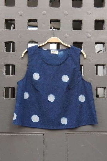 indigo denim and white  block moon print sleeveless tank top with round neck on a wooden hanger in front of a grey grid door