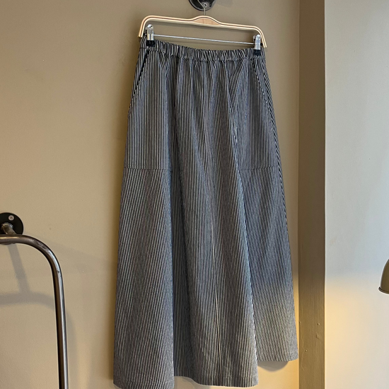 Gray skirt hanging on a rack against a beige wall.