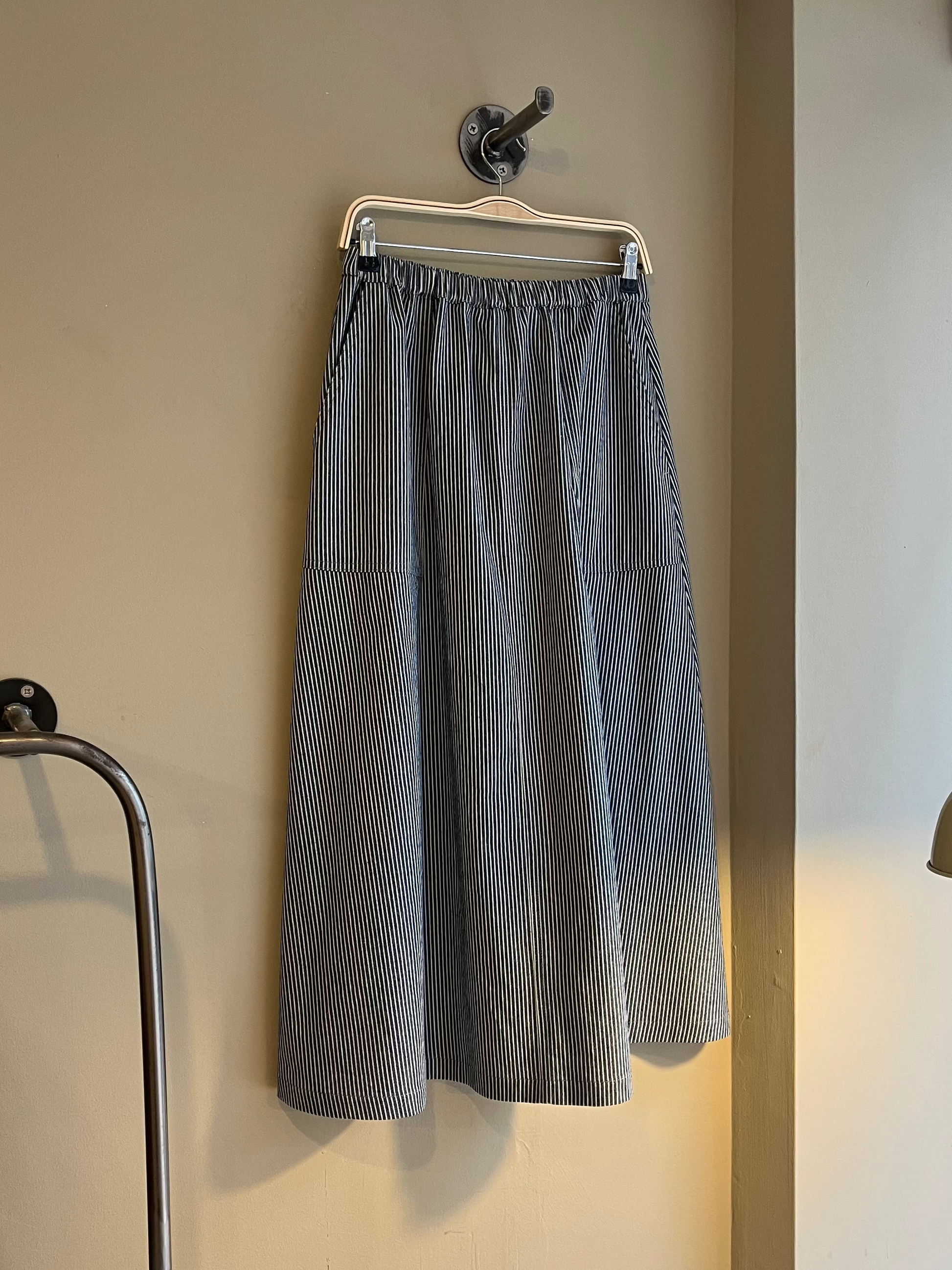 Gray skirt hanging on a rack against a beige wall.