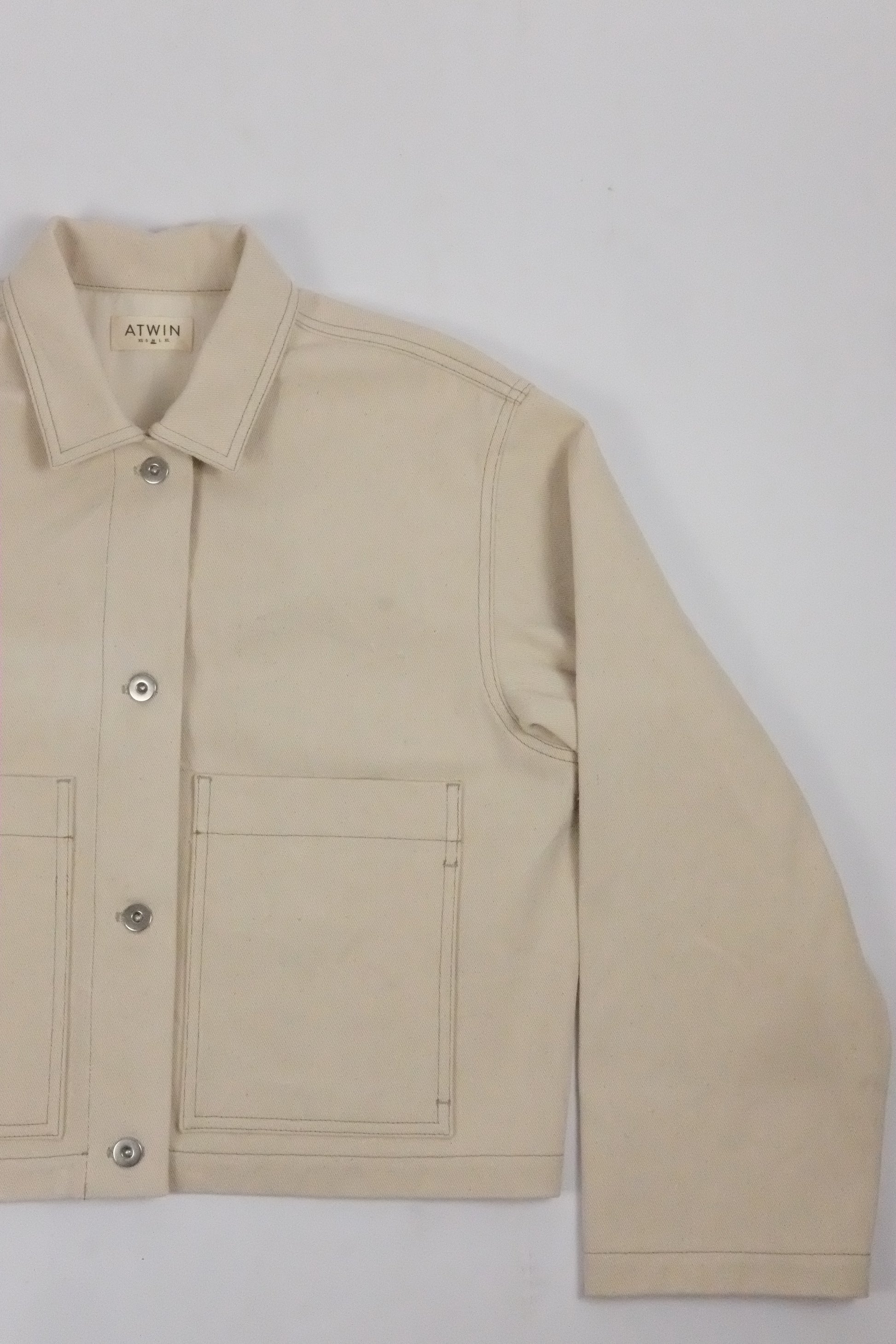 Beige jacket with a brand label on a light gray background