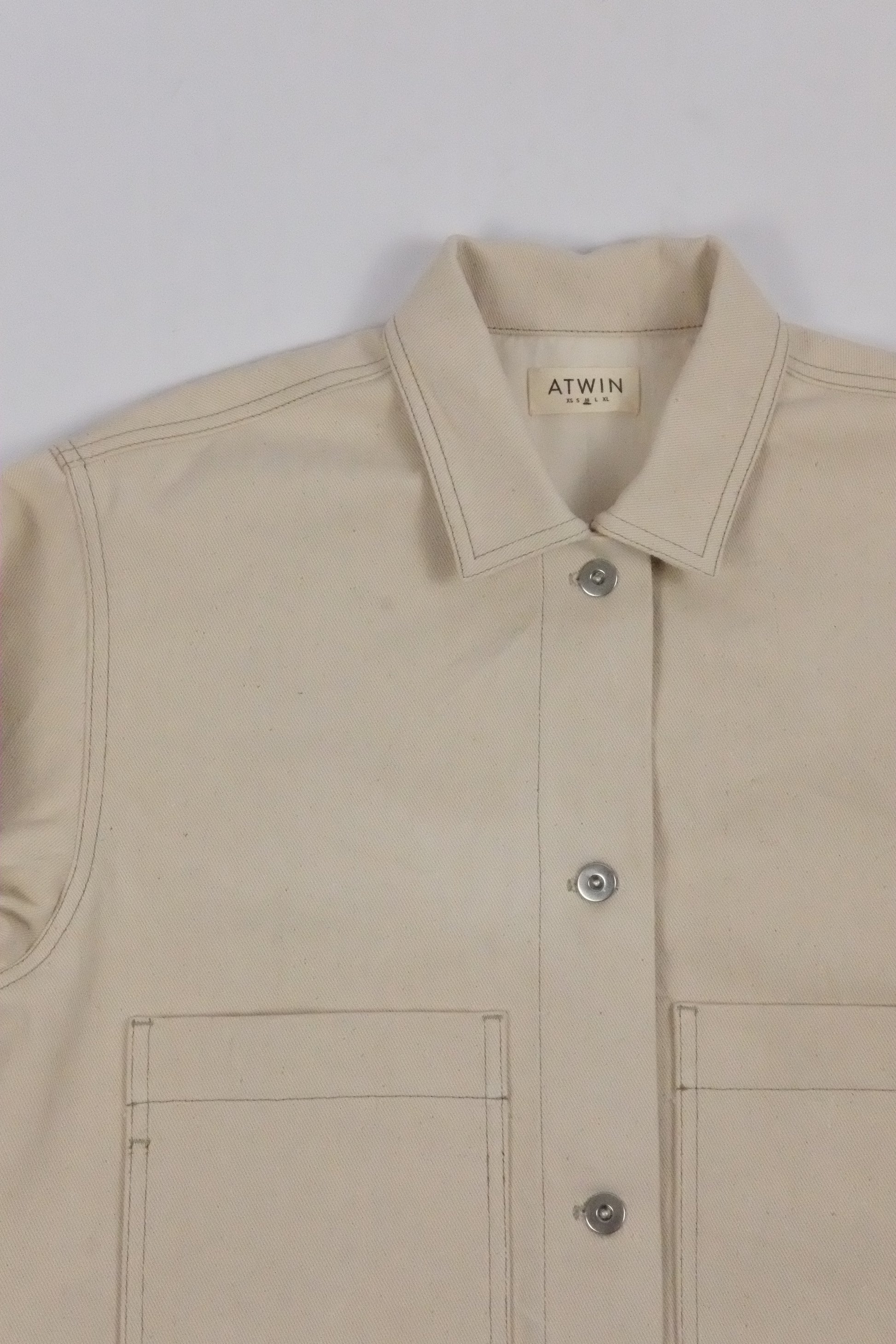 Beige jacket with a brand label on a light gray background