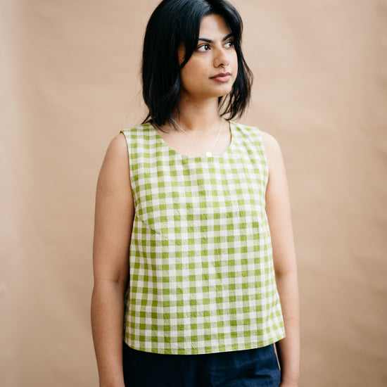 Woman wearing a green and white checkered top against a beige background