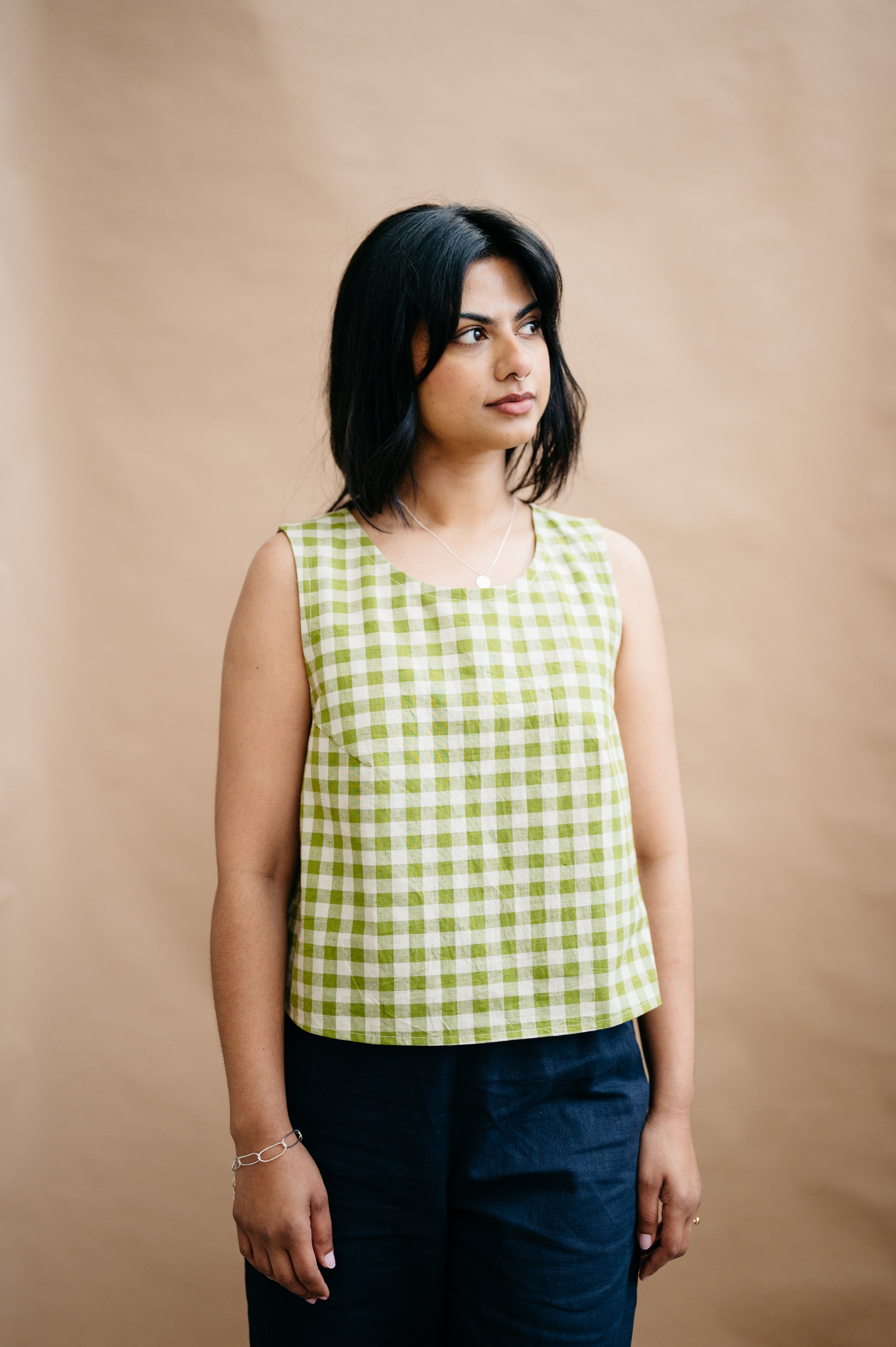 Woman wearing a green and white checkered top against a beige background