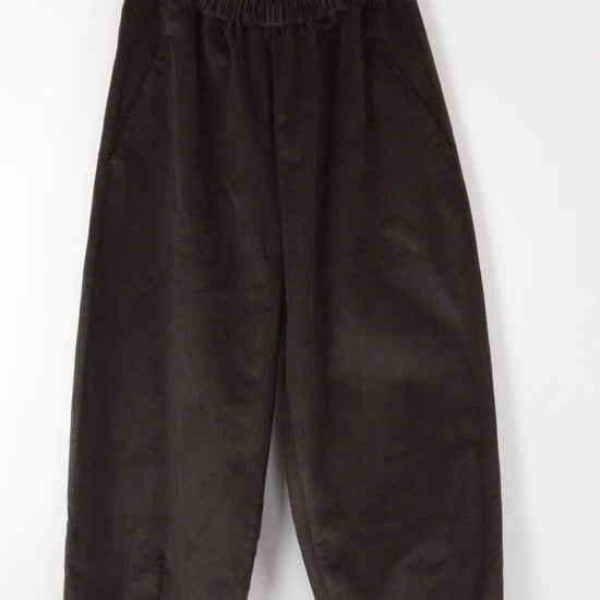 brown cord barrel leg trousers hanging on a white background