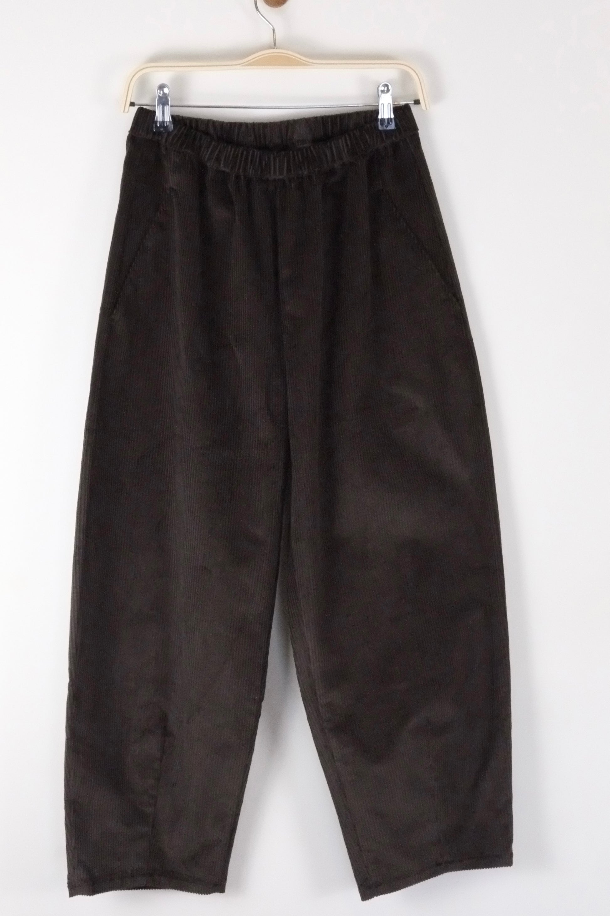 brown cord barrel leg trousers hanging on a white background