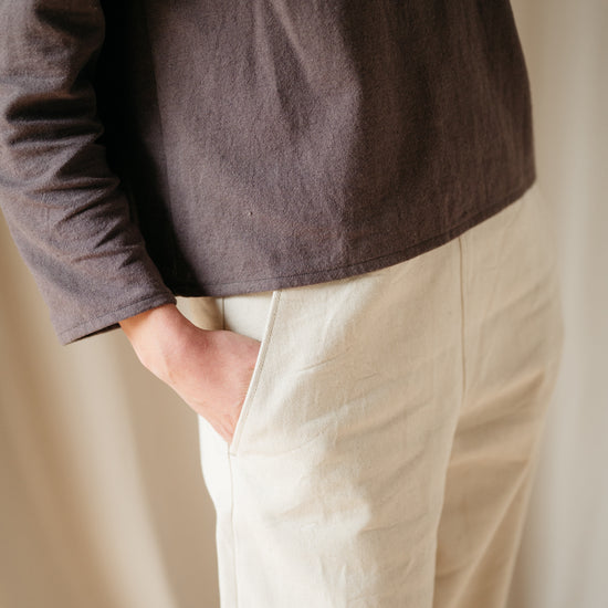 Model wearing barrel leg denim trousers, side view
