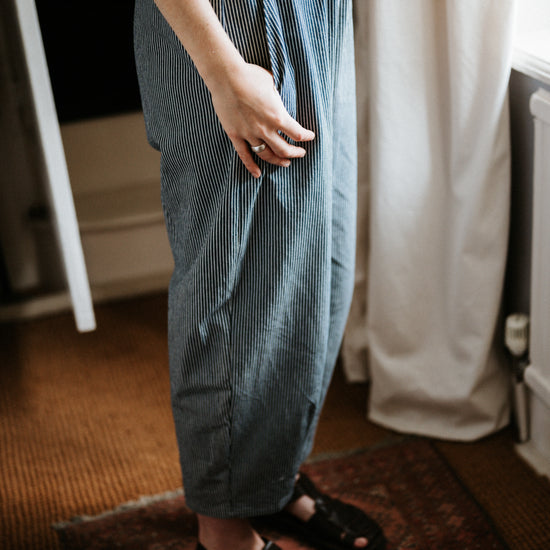 Person wearing blue striped denim trousers and sandals indoors.