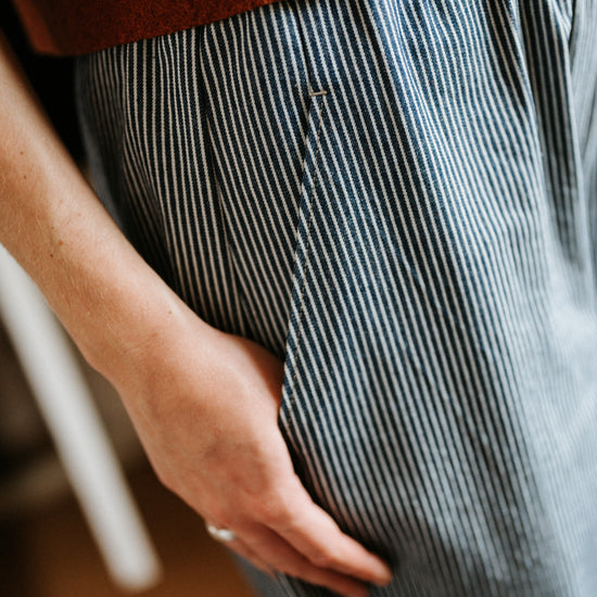 Person wearing a brown top and blue striped denim jeans with a blurred background