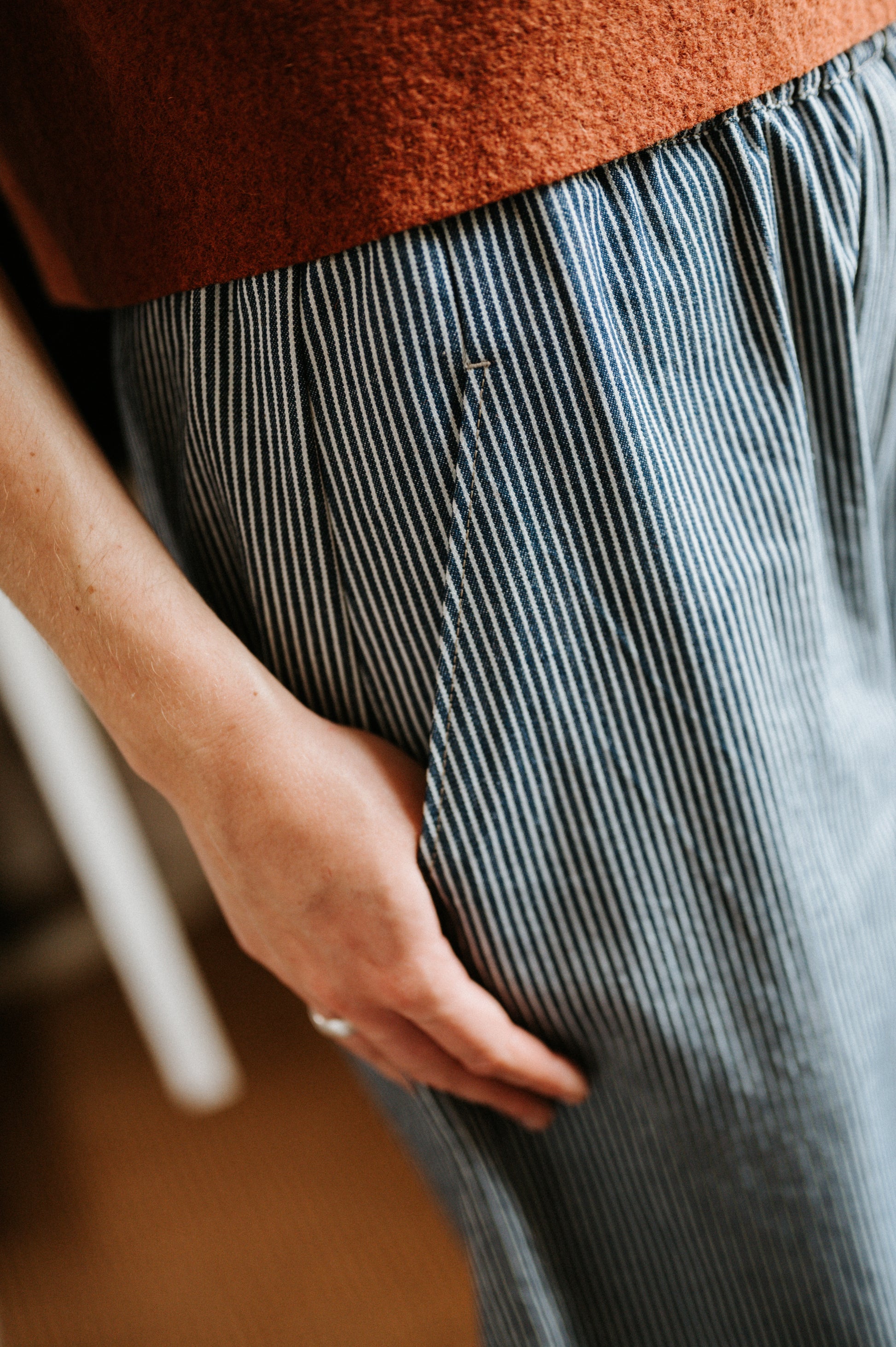 Person wearing a brown top and blue striped denim jeans with a blurred background