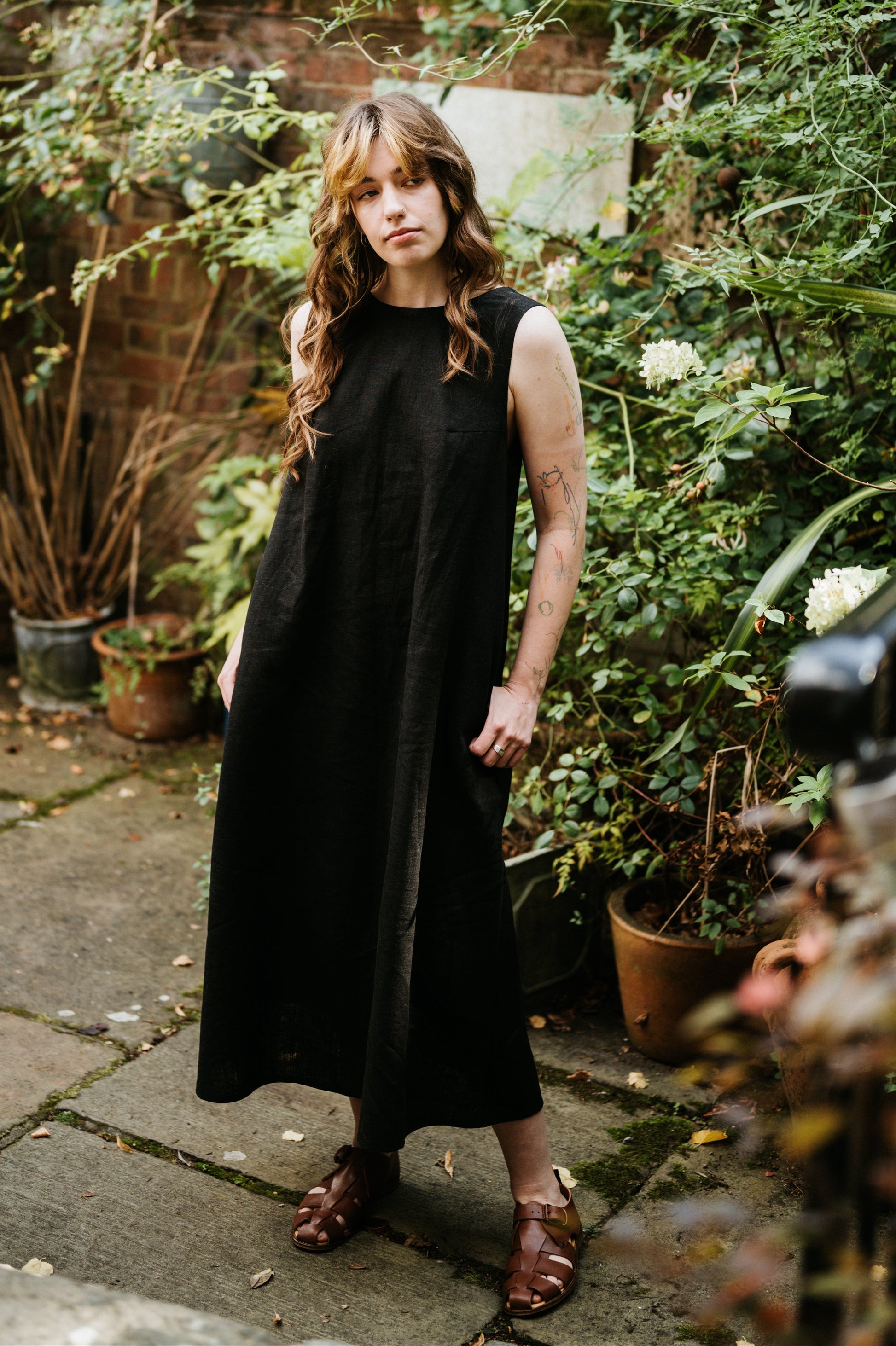 Woman in a black dress standing in a garden setting
