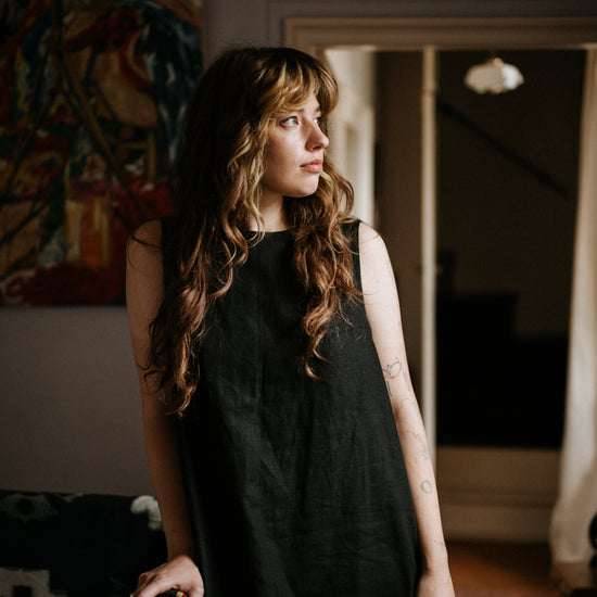woman standing against a banister wearing a midaxi black ramie linen dress