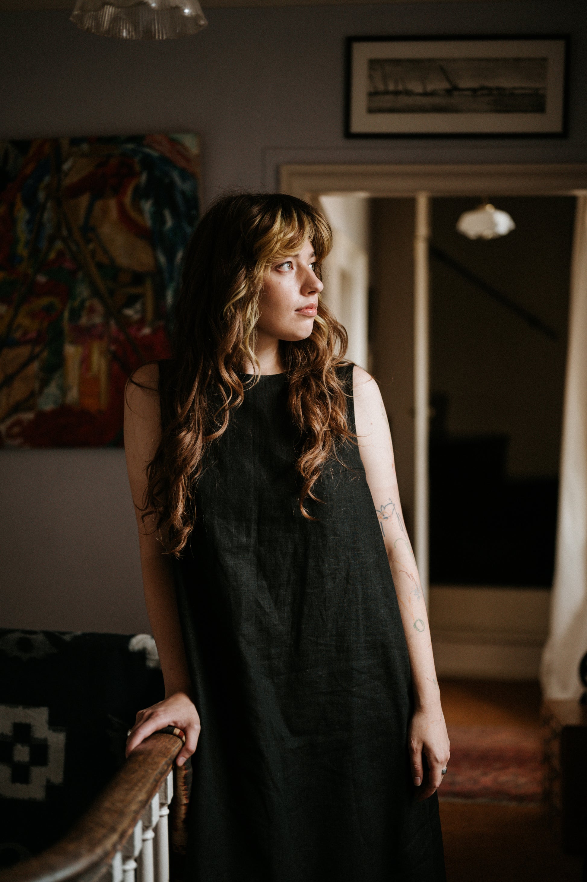 woman standing against a banister wearing a midaxi black ramie linen dress
