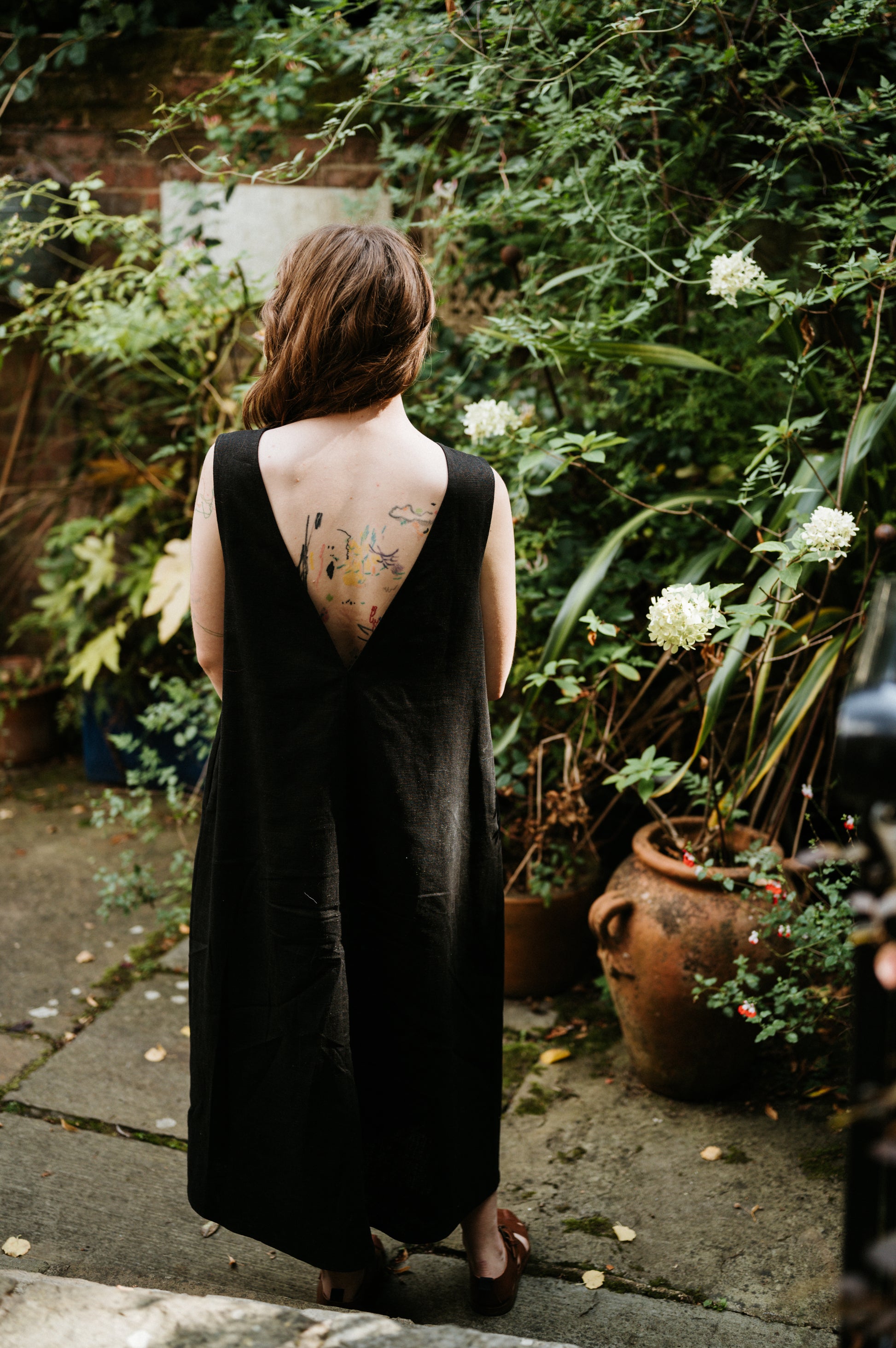 woman wearing a long black linen dress in a garden setting