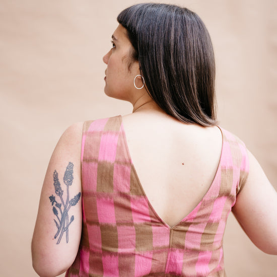 Woman wearing a pink and brown checkered dress with a beige background