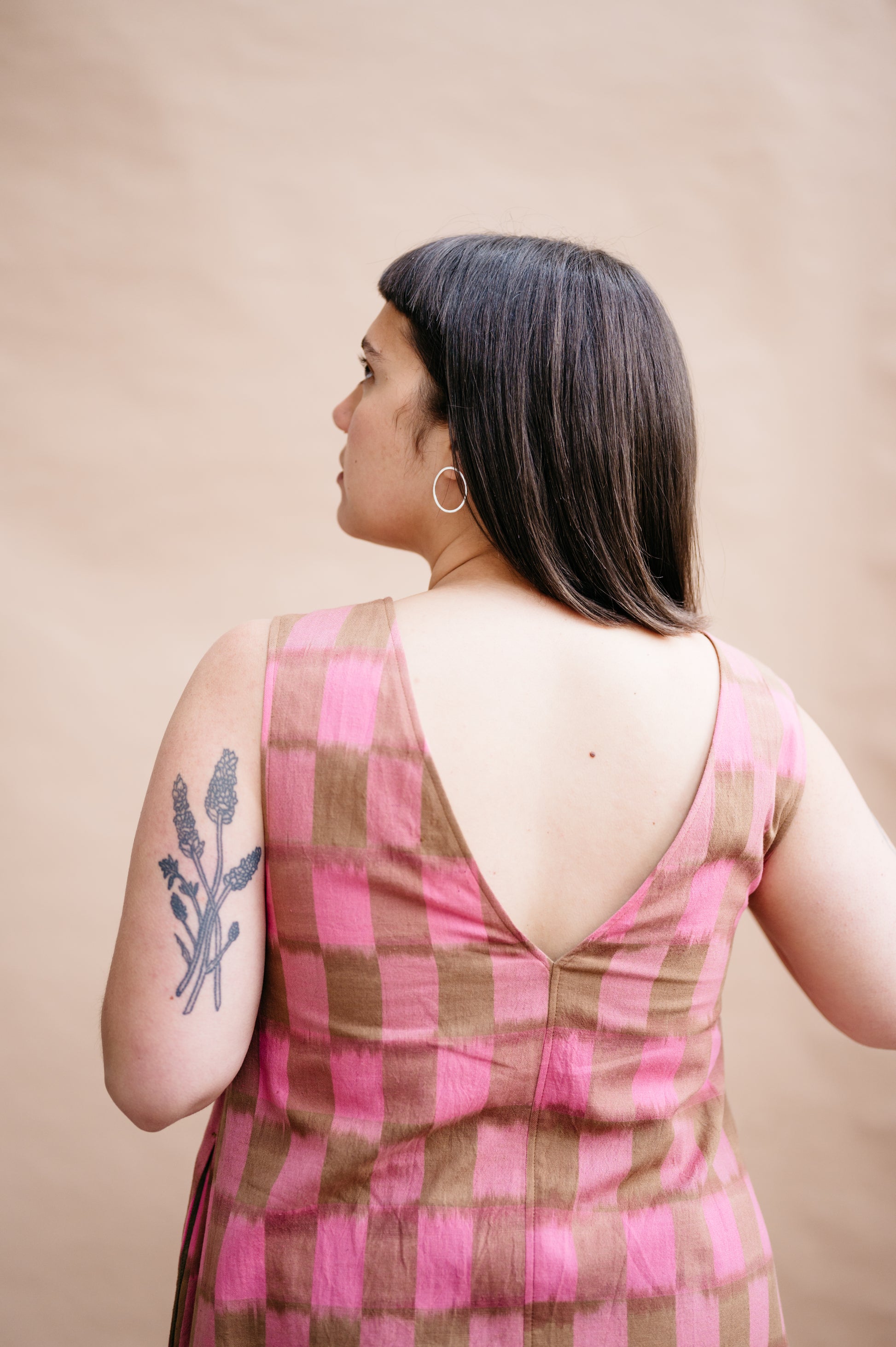 Woman wearing a pink and brown checkered dress with a beige background