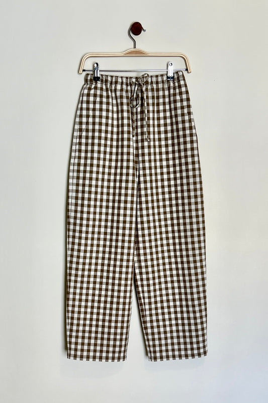 A pair of brown cotton gingham daily trousers with a straight-fit design, high-waisted, with a slim elasticated waistband and drawstring, featuring pockets.