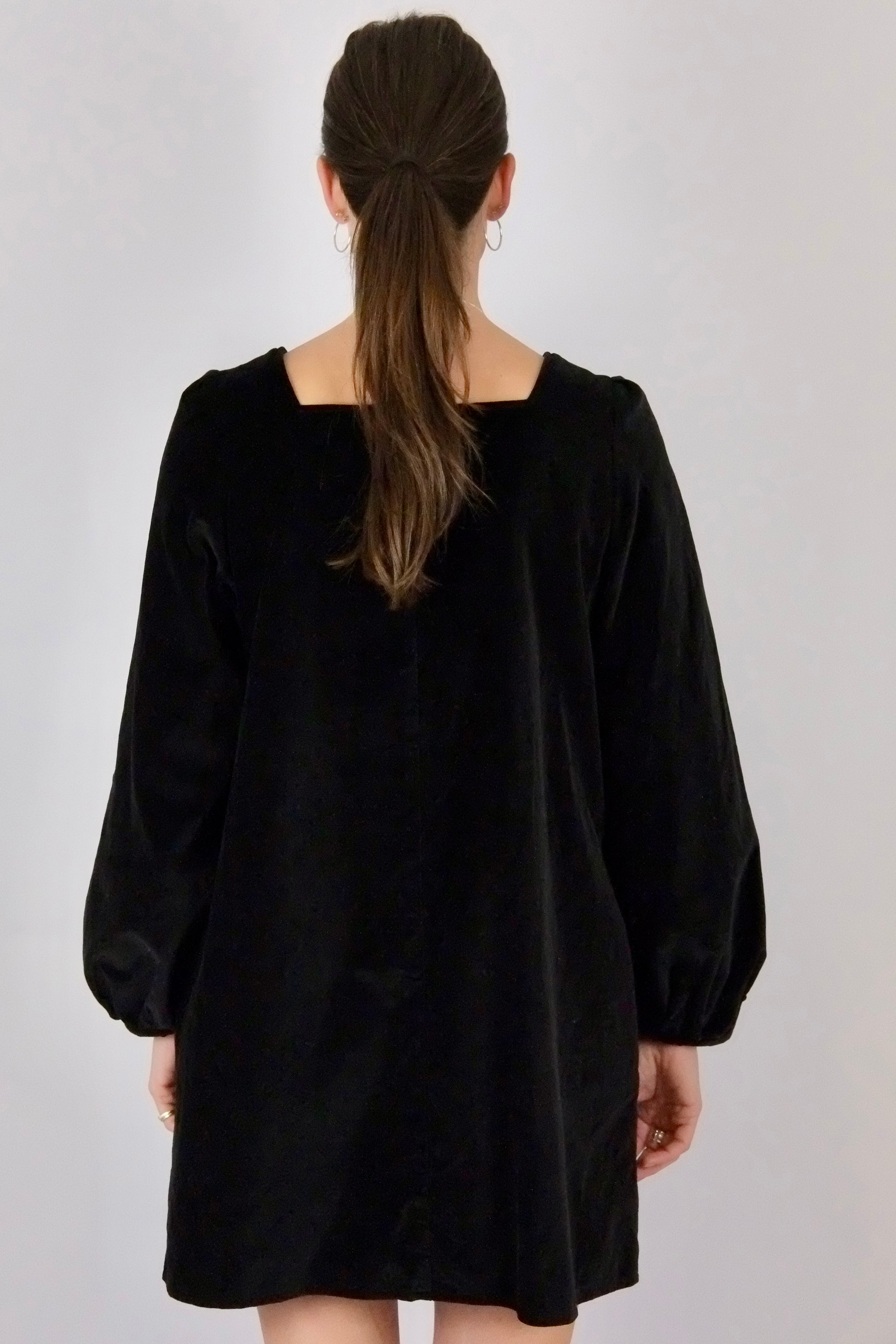 Black mini dress worn by a person with a plain background