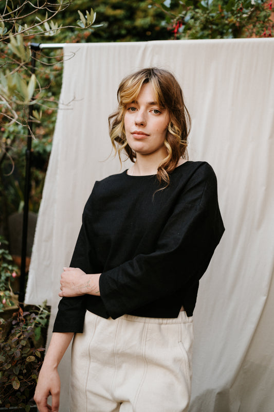 woman wearing black reversible top in ramie linen standing in a garden setting