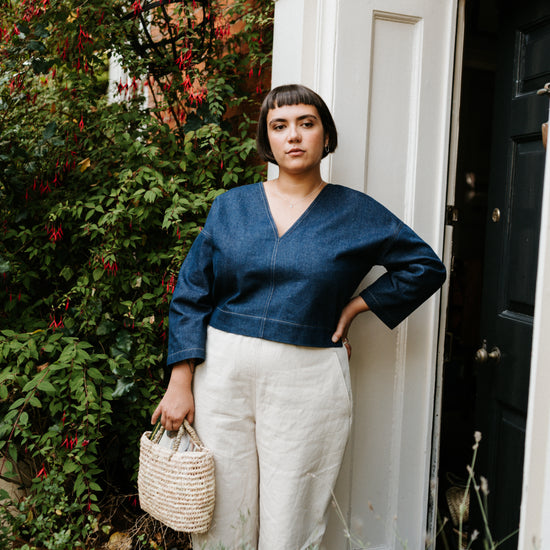 Woman standing in front of a door with plants and flowers around