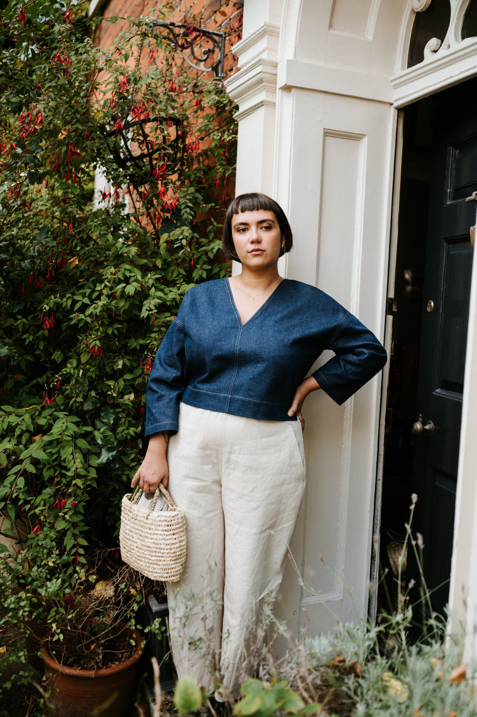 Woman standing in front of a door with plants and flowers around