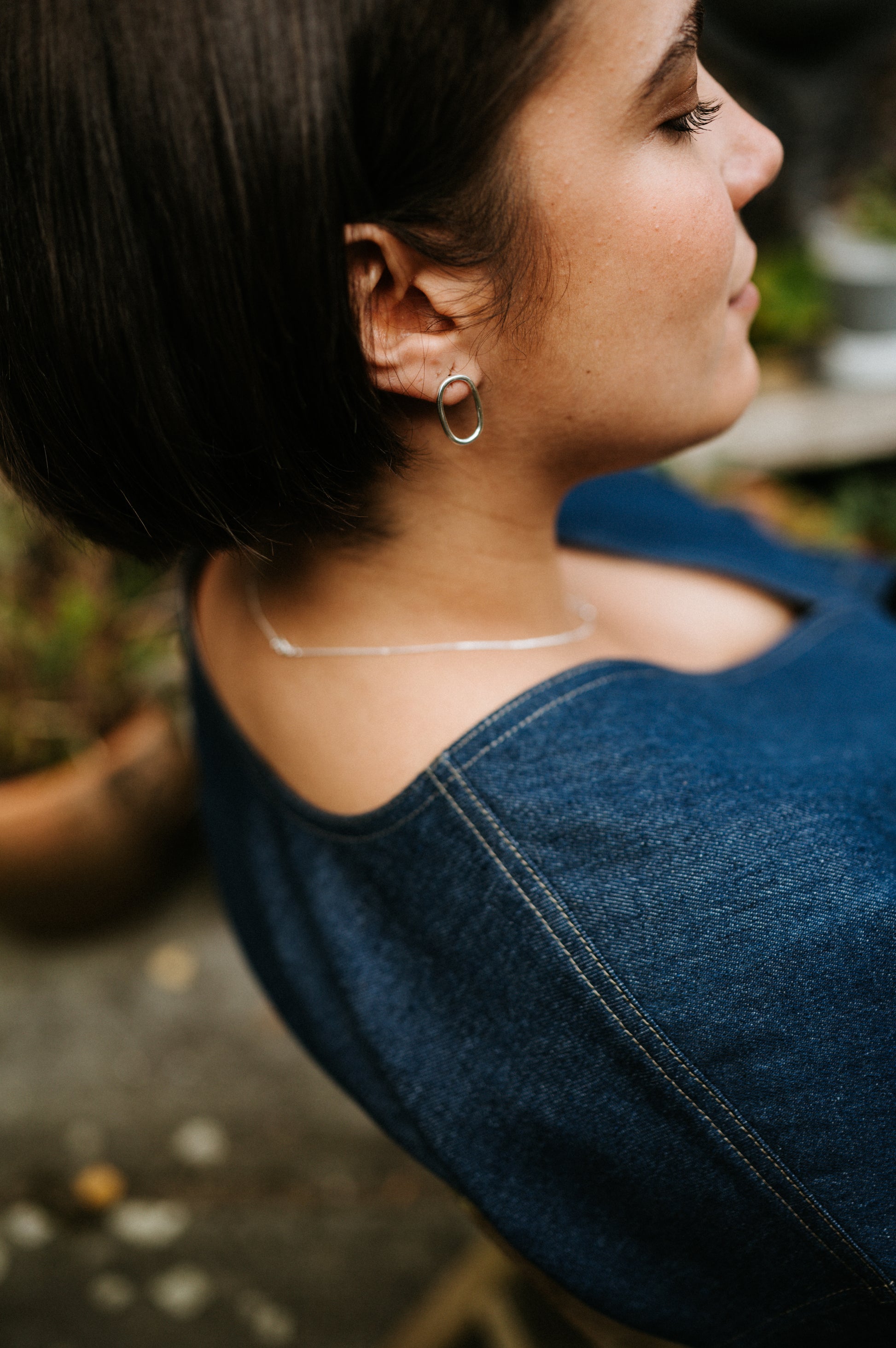 Close-up of a person wearing a blue denim top with a blurred background