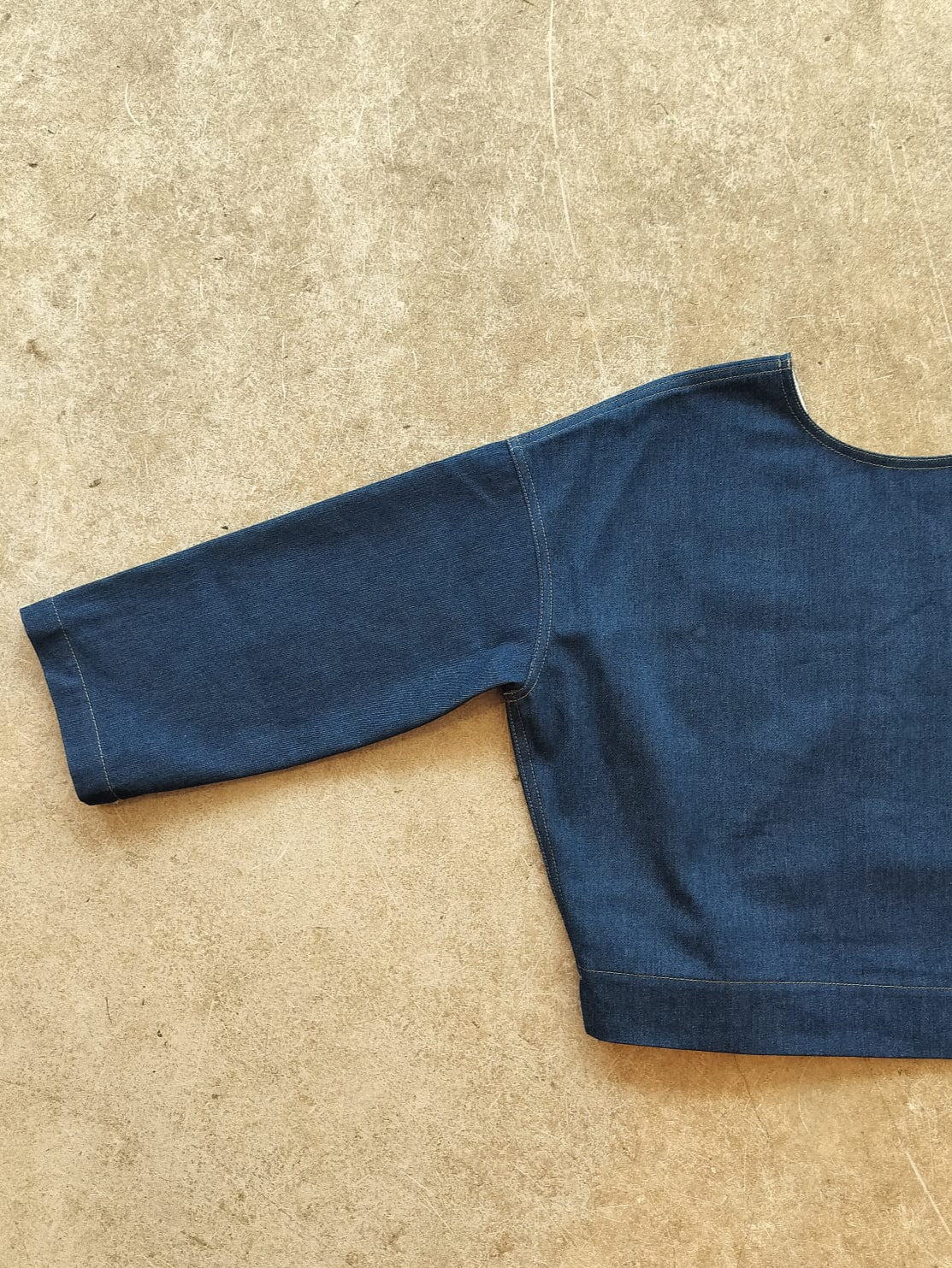 Blue denim top on a beige surface