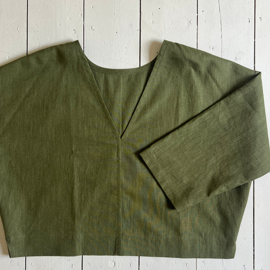 Khaki ramie linen reversible top laid flat on a wooden surface.