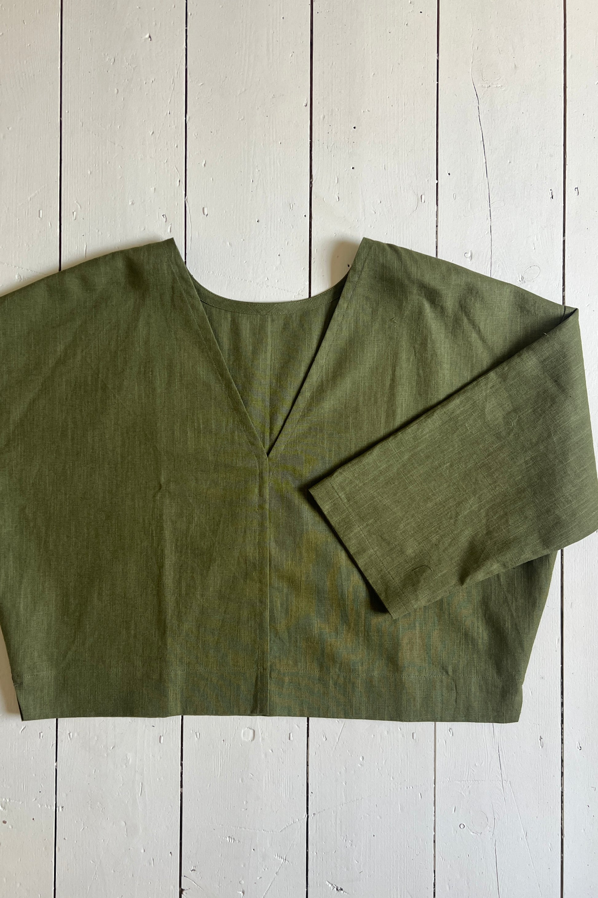 Khaki ramie linen reversible top laid flat on a wooden surface.