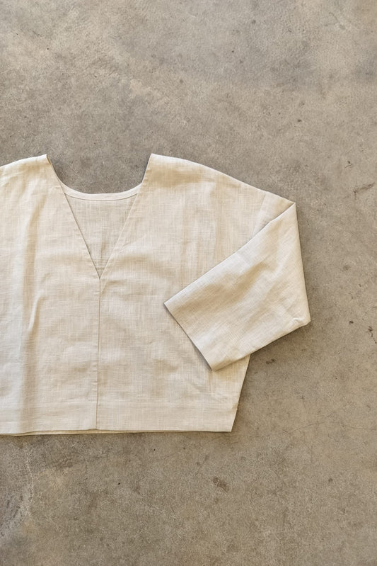 Beige reversible top on a textured gray surface