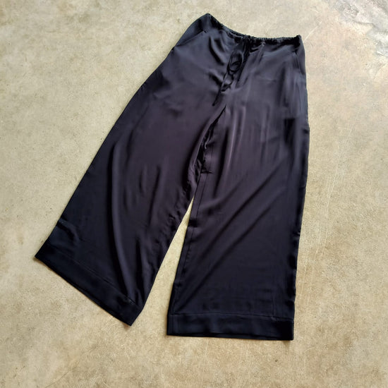 Black Slinky trousers on a concrete floor
