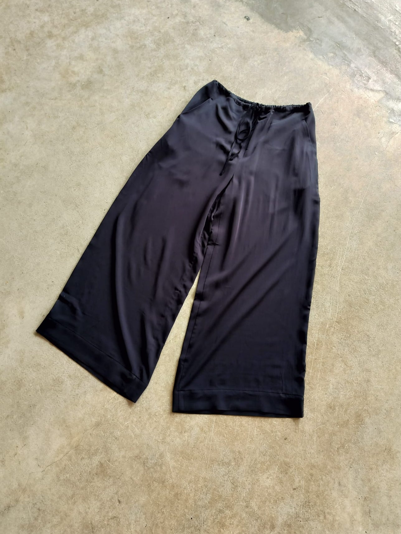 Black Slinky trousers on a concrete floor