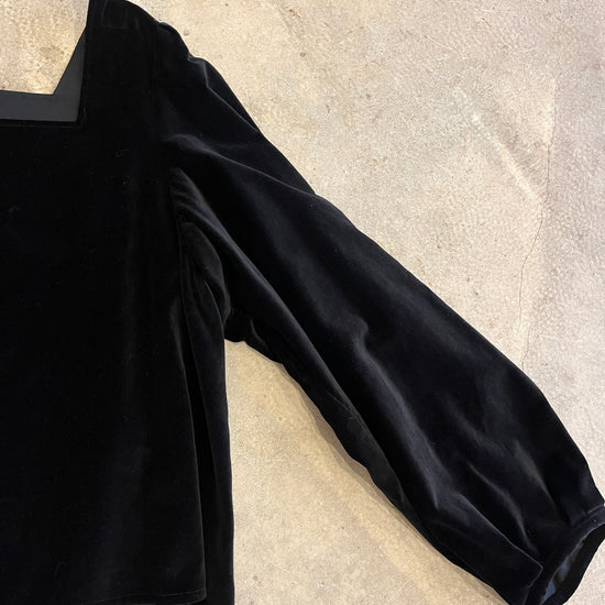 Black long-sleeve top on a light gray surface